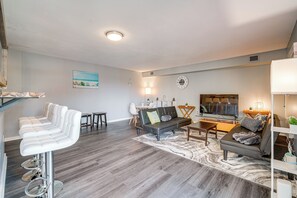 A modern living room with a sofa, a dining area, and a bar stool. - Walk to Casino: Condo w/ Balcony in Atlantic City! (Atlantic City)