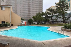 A swimming pool with clear blue water, surrounded by a paved deck and a low brick wall. - Walk to Casino: Condo w/ Balcony in Atlantic City! (Atlantic City)