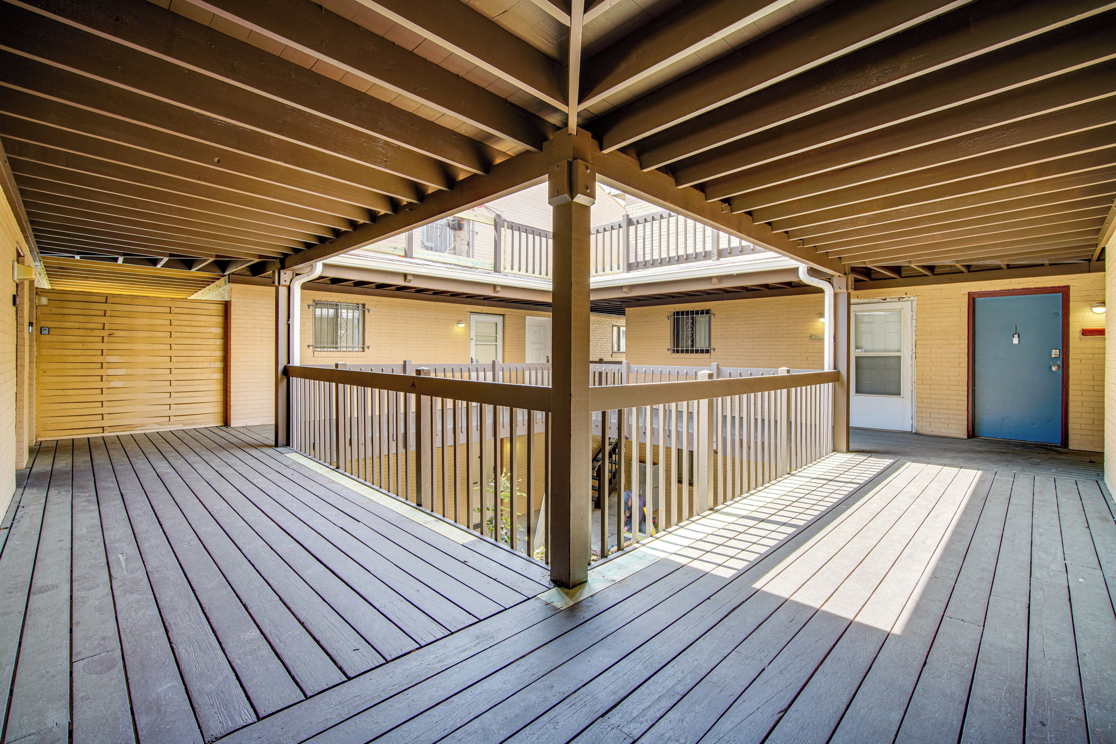 Une terrasse extérieure en bois, dotée d’une rambarde, d’une porte et d’une fenêtre.