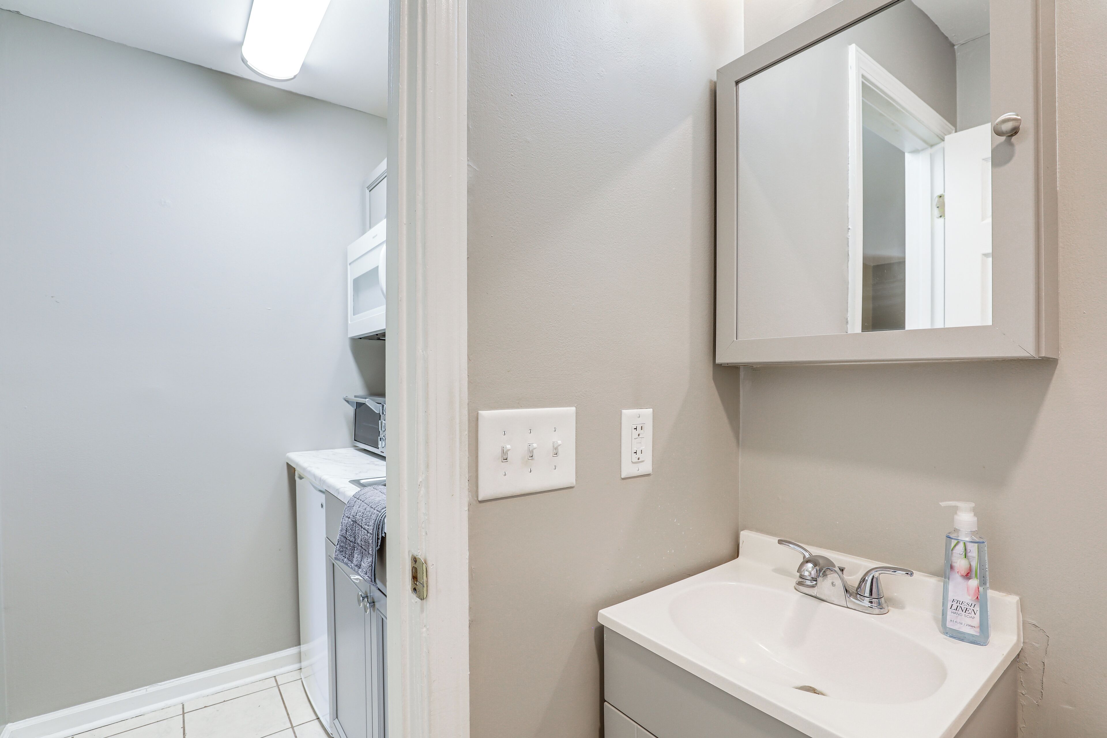 Un baño con lavamanos blanco, un espejo y zona de ducha.