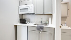 Une cuisine de taille réduite avec des meubles blancs, un four à micro-ondes, un grille-pain et un évier.