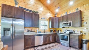 Una cocina moderna con armarios de madera, electrodomésticos de acero inoxidable y un ventanal que proporciona luz natural.