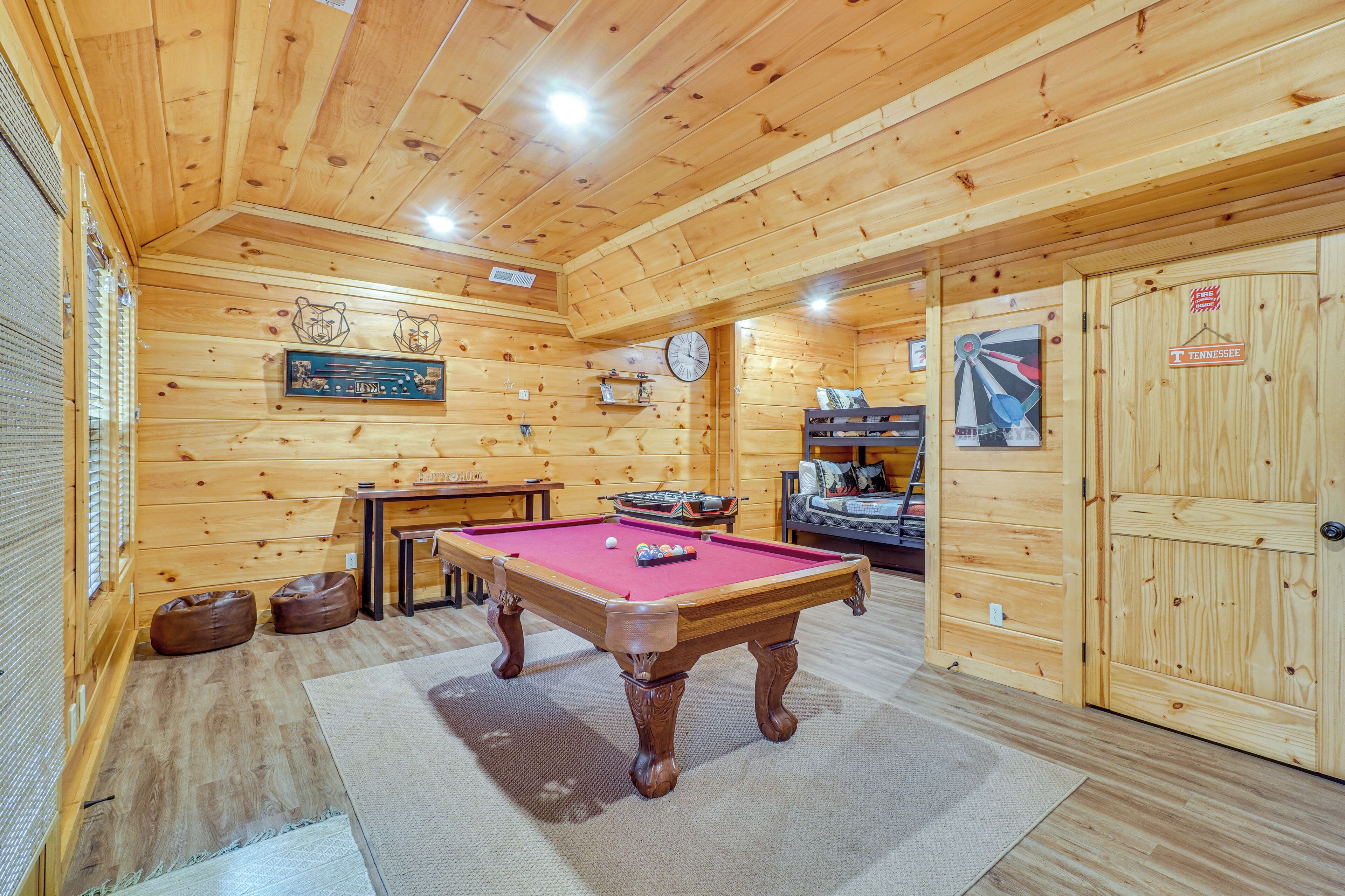 A wooden room with a pool table, a clock, and a Tennessee sign.