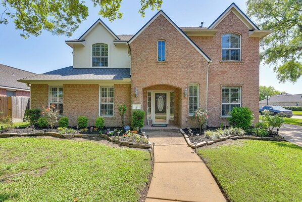 A two-story brick house with a front entrance, a covered porch, and a well-maintained lawn. - Patio, BBQ & Yard: Family Retreat in Pearland (Pearland)