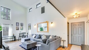 A spacious living room with a grey sectional sofa, a small round table, and a large mirror on the wall.