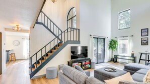 A modern living room with a staircase, a television, and a dining area.