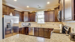 Una cocina con encimeras de granito, electrodomésticos de acero inoxidable y armarios de madera oscura.