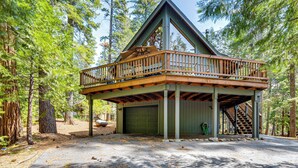 Eine Holzhütte mit einer Holzterrasse, einer Garage und einer Treppe, die zum oberen Stockwerk führt.