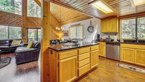 Eine geräumige Küche mit Holzausstattung, einer großen Kücheninsel und einem Essbereich mit einer Ledersofa.