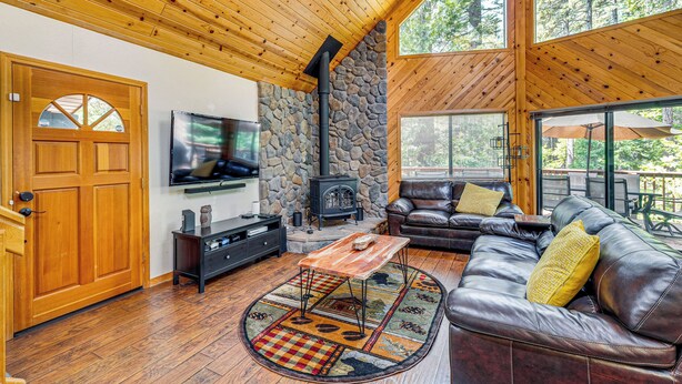 Ein gemütliches Wohnzimmer mit Kamin aus Stein, Ledersofa und Fernseher.