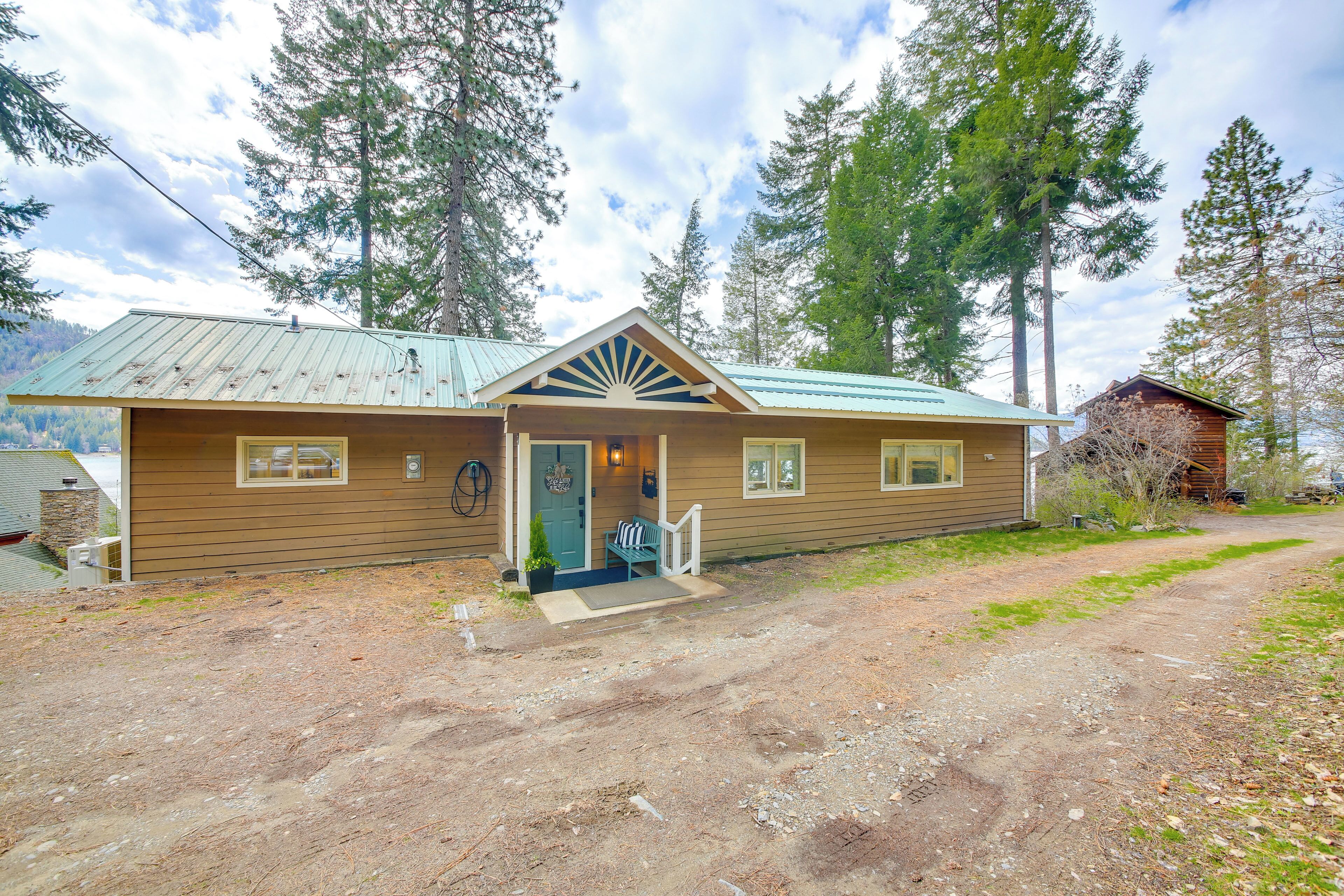 A wooden cabin with a metal roof, a porch with a bench, and a small front yard.