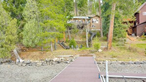 A wooden cabin with a deck and stairs leading to a second-story balcony. - Peaceful Cabin w/ Dock on Lake Pend Oreille (Sagle)
