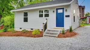 A small, single-story house with a blue front door, white siding, and a gravel driveway. - 2 Mi to Downtown: Greensboro Home By Park! (Greensboro)