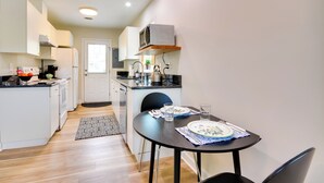A compact kitchen with white cabinets, a microwave, and a dining area with a table set for two. - 2 Mi to Downtown: Greensboro Home By Park! (Greensboro)