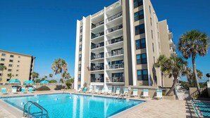 Un hôtel doté d’une piscine, de plusieurs balcons et de palmiers.