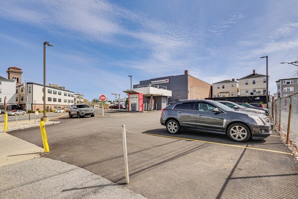 A parking lot with a silver SUV, buildings in the background, and a clear sky. - Lively Area: Downtown Providence Apartment! (Providence)