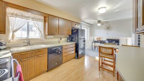Une cuisine dotée de meubles en bois, d’un lave-vaisselle, d’un réfrig érateur et d’un coin repas comprenant une chaise et une table.