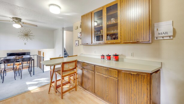 Una cocina con armarios de madera, un comedor con mesa y sillas, y un ventilador de techo.