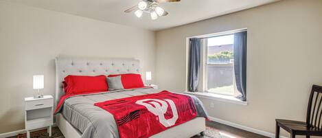 A bedroom with a bed, nightstand, and a window with curtains.