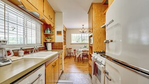 Eine Küche mit Holzausstattung, einem weißen Kühlschrank und einem Essbereich mit Tisch und Stühlen.