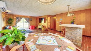 Ein geräumiger Raum mit einem großen Holzespeise-tisch, einer Bar und einer gemütlichen Sitzecke mit einer Couch und Sesseln.