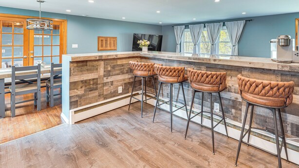 Une cuisine avec des tabourets de bar en bois, un îlot central en bois et un coin repas comprenant une table et des chaises.