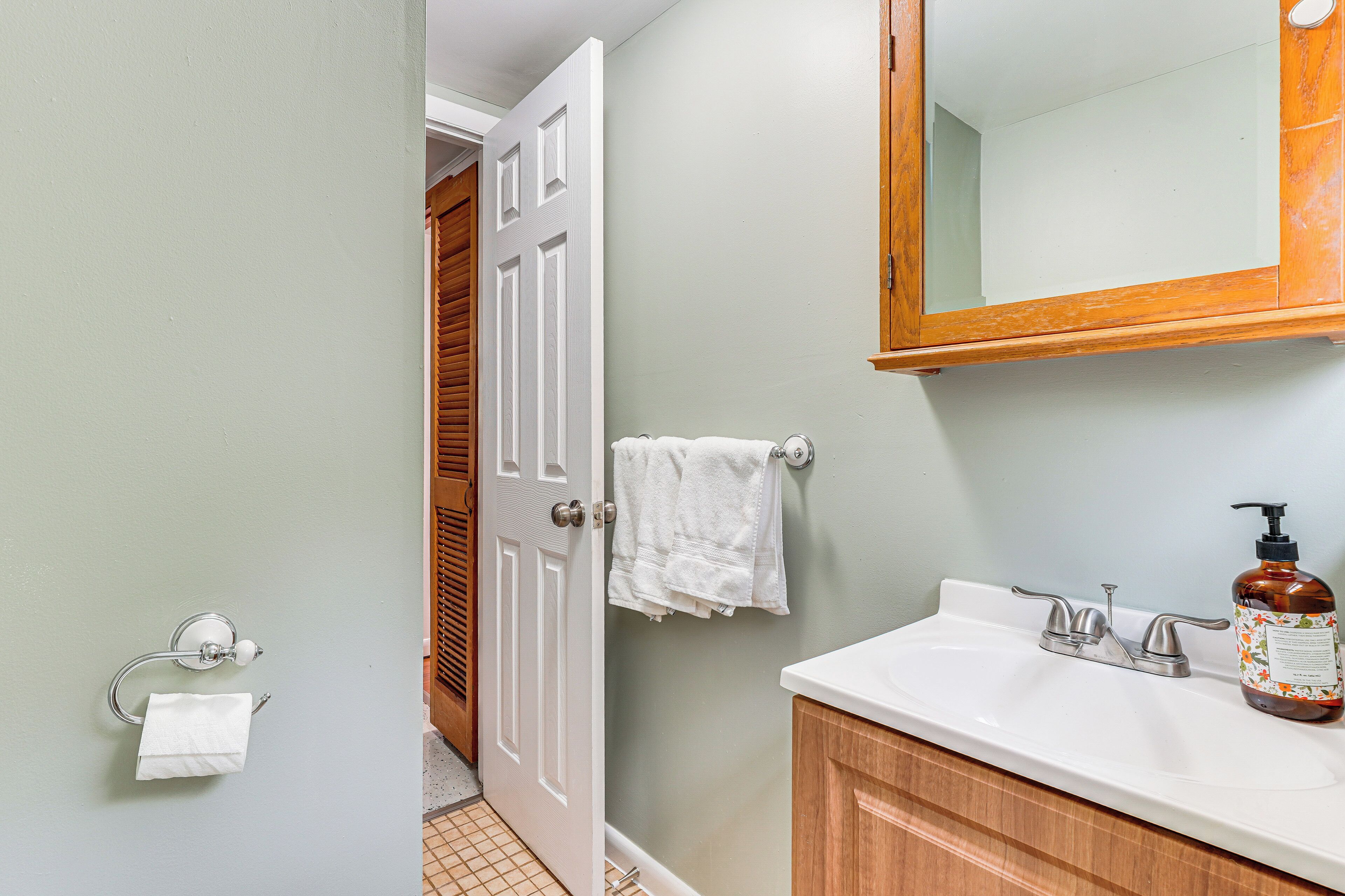 A bathroom with a white sink, a wooden cabinet, a mirror, and a towel hanging on the wall.
