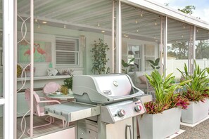 An outdoor patio with a grill, seating, and potted plants.