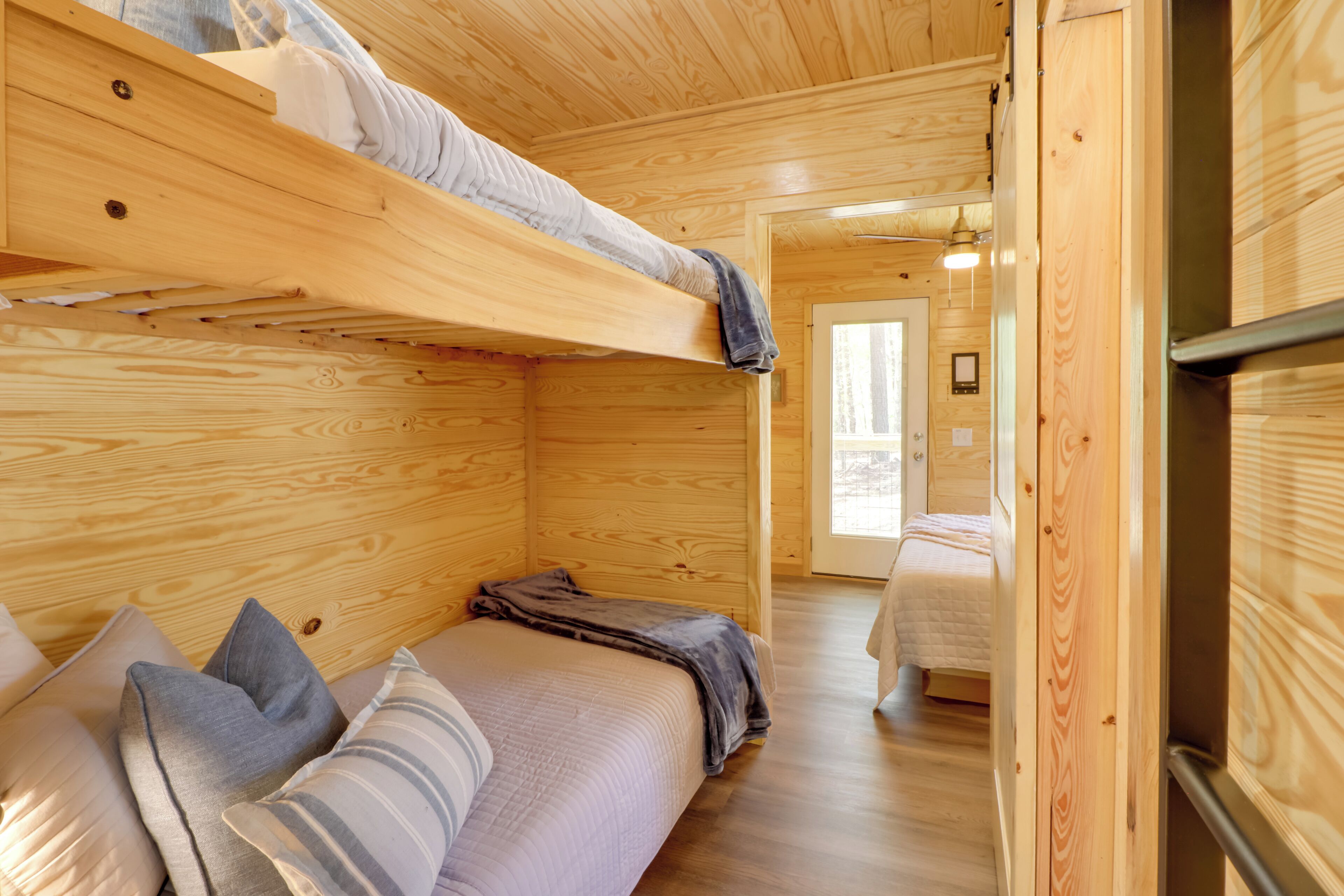 A cozy cabin interior with a bunk bed, a sofa, and a door leading to another room.
