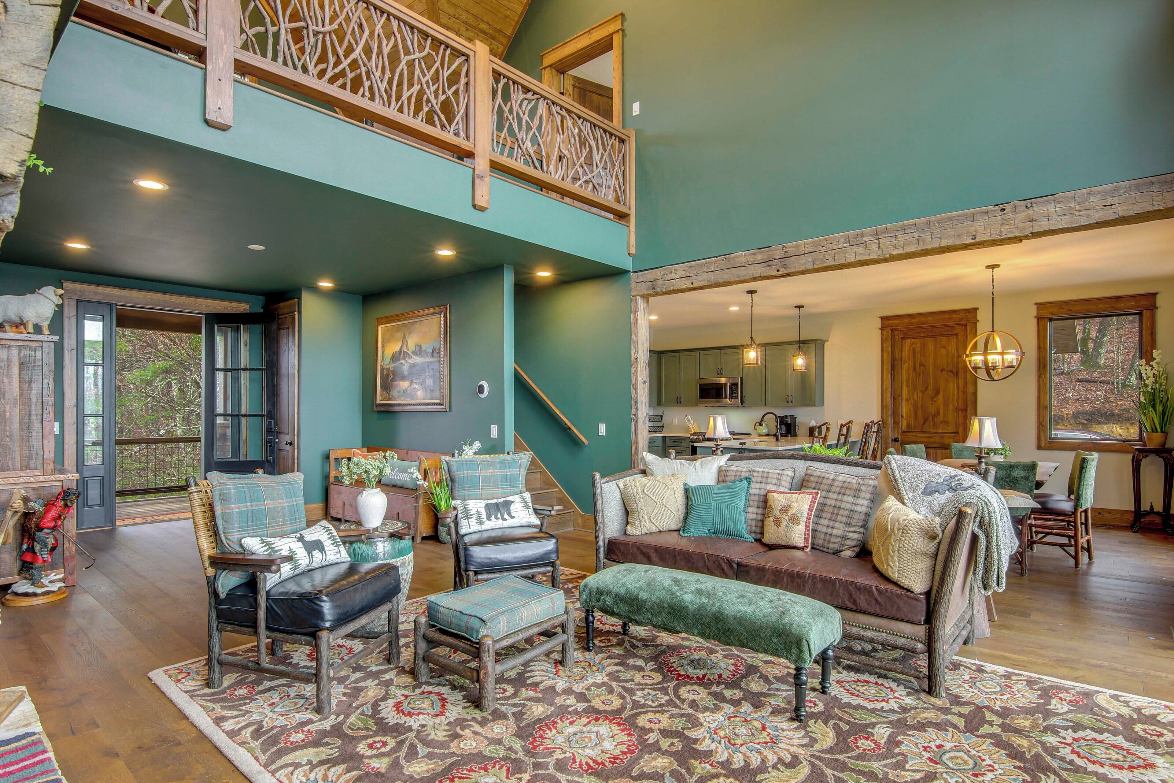 A spacious living area with a high ceiling, wooden staircase, and a view of the kitchen.