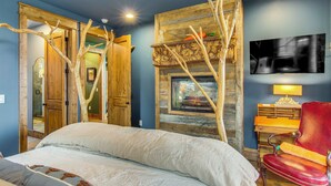 A bedroom with a bed, a wooden wardrobe, a fireplace, a red chair, and a television on the wall. - Scenic Sanctuary w/ Mtn Views: Glenville Lodge (Glenville)