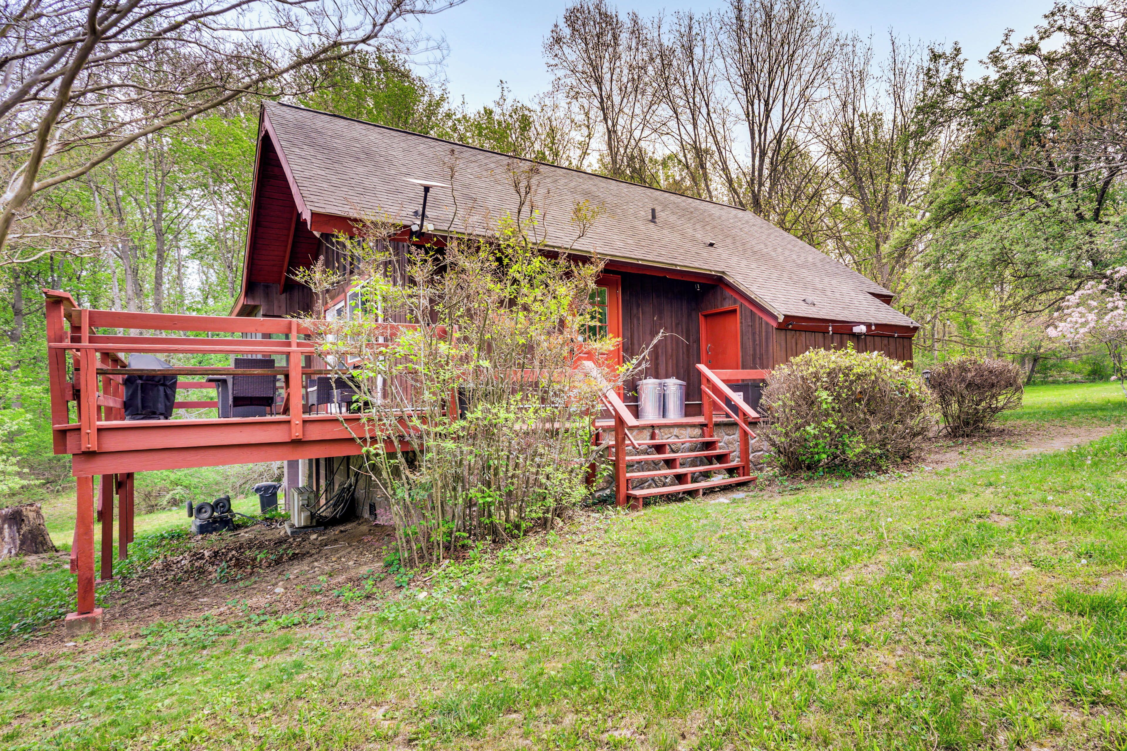 Ein rustikaler Schuppen mit roter Fassade, einer Holzdielen-Terrasse und einem Steinfundament.