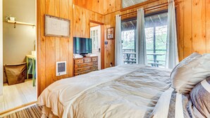 Ein Schlafzimmer mit Holzwänden, einem Bett, einer Kommode und einem Fenster mit Vorhängen.
