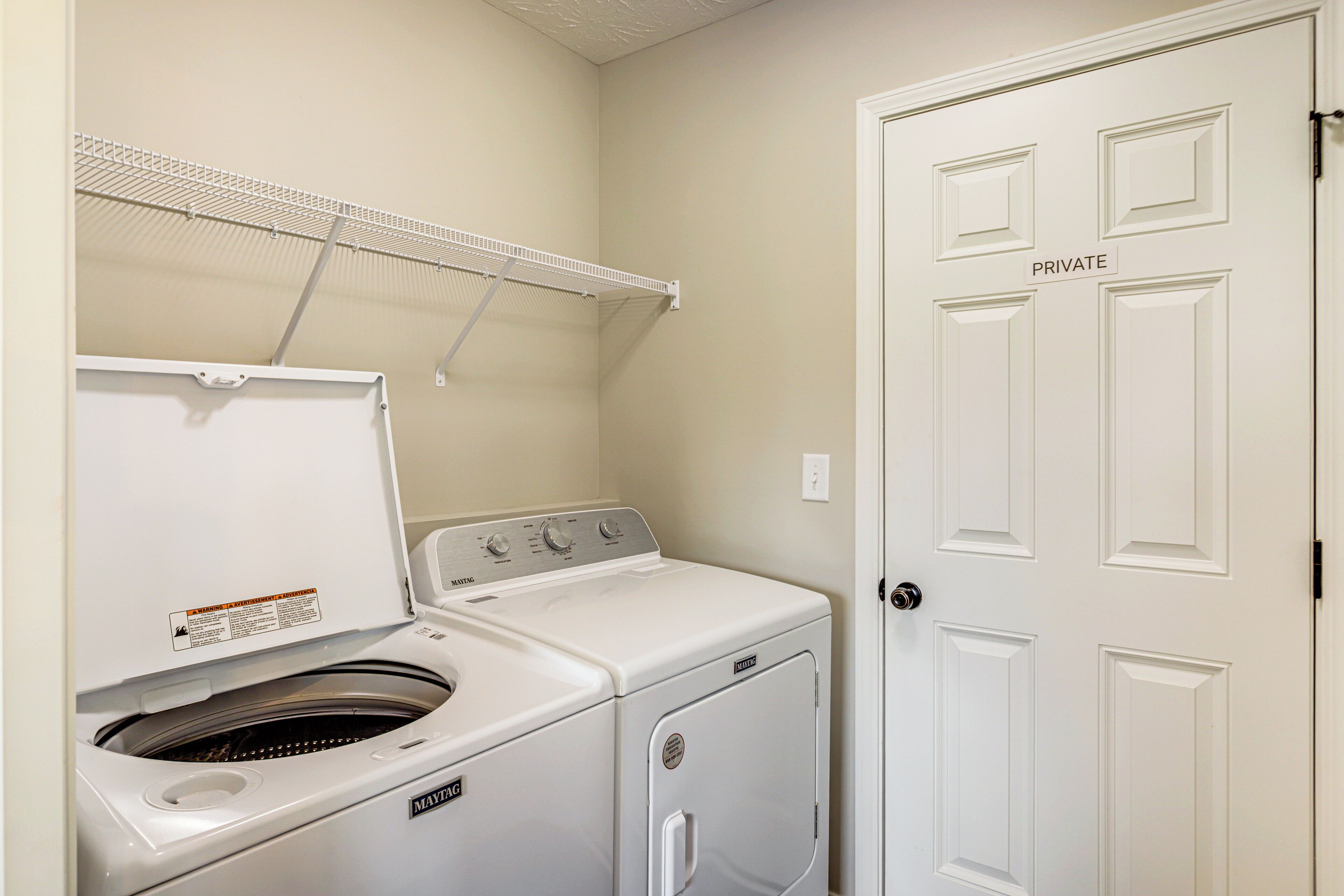 A laundry room with a washing machine, dryer, and a clothes drying rack.