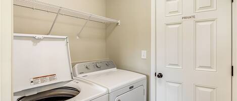 A laundry room with a washing machine, dryer, and a clothes drying rack.