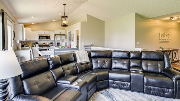 A modern living room with a black leather sectional sofa, a dining area, and a kitchen in the background. - Deck & Outdoor Dining: Family Getaway in Dry Ridge (Dry Ridge)