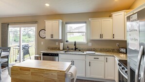 A modern kitchen with white cabinets, a granite countertop, a built-in oven, and a refrigerator. - Deck & Outdoor Dining: Family Getaway in Dry Ridge (Dry Ridge)