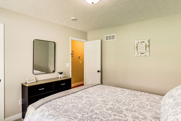 A bedroom with a bed, a dresser, a mirror, and a door leading to another room. - Deck & Outdoor Dining: Family Getaway in Dry Ridge (Dry Ridge)