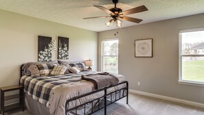 A bedroom with a bed, a ceiling fan, a window, and artwork on the walls. - Deck & Outdoor Dining: Family Getaway in Dry Ridge (Dry Ridge)