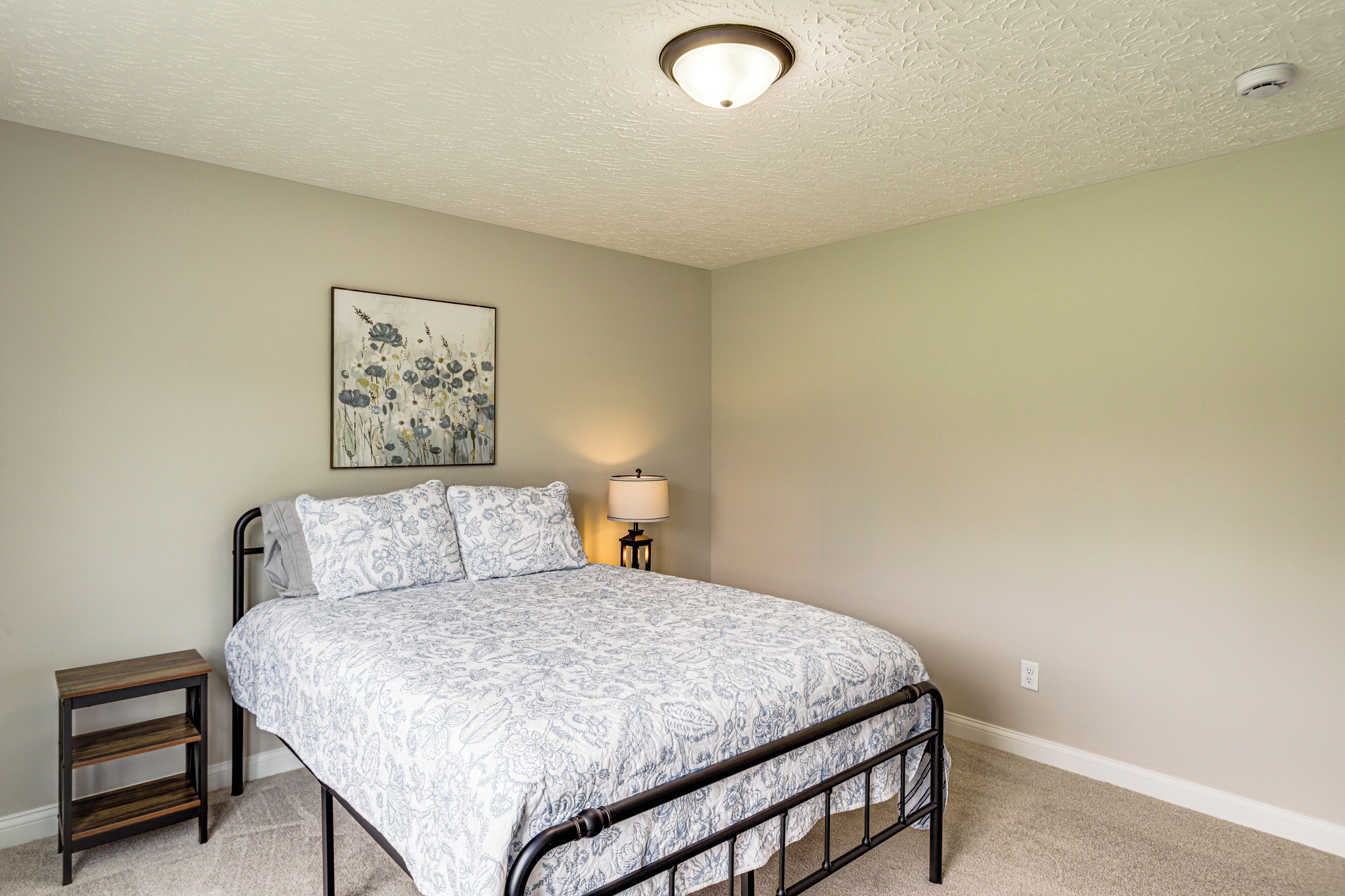 A bedroom with a bed, a bedside table, a lamp, and a ceiling light fixture.