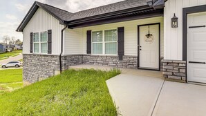 A two-story house with a stone foundation, a front porch, and a garage. - Deck & Outdoor Dining: Family Getaway in Dry Ridge (Dry Ridge)