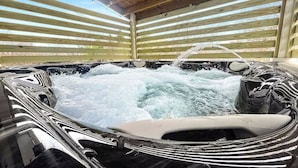 A hot tub with water jets, surrounded by wooden slats and a wooden ceiling. - Spacious Home Chef's Kitchen, BBQ Grill, 5 Min Cle Clinic, Hot Tub, ADA, King (Cleveland)
