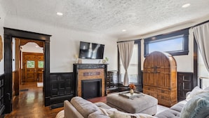 A living room with a fireplace, a television mounted above it, and a large wooden cabinet. - Spacious Home Chef's Kitchen, BBQ Grill, 5 Min Cle Clinic, Hot Tub, ADA, King (Cleveland)