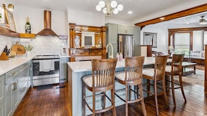 A modern kitchen with a central island, wooden chairs, and a stainless steel refrigerator. - Spacious Home Chef's Kitchen, BBQ Grill, 5 Min Cle Clinic, Hot Tub, ADA, King (Cleveland)