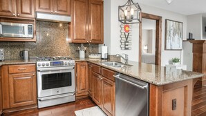 A modern kitchen with wooden cabinets, stainless steel appliances, granite countertops, and a built-in dishwasher.