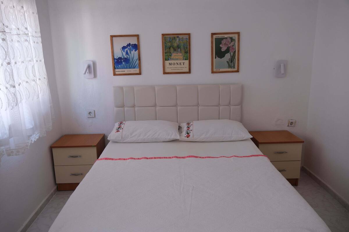 Un dormitorio con una cama grande, dos mesitas de noche y tres cuadros en la pared.