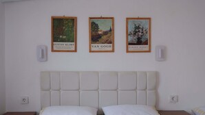 Een slaapkamer met een groot bed, twee nachtkastjes en drie ingelijste kunstwerken aan de muur.