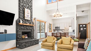 A spacious living room with a stone fireplace, comfortable seating, a dining area, and a kitchen in the background. - Central, Top Floor Unit, Close to Lift and Town (Breckenridge)