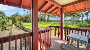 A covered outdoor area with a wooden deck, a table, and chairs. - NEW! Village Manor D21, Distant Ocean Views, Walk to Kapaa Town and Beach (Kapaa)