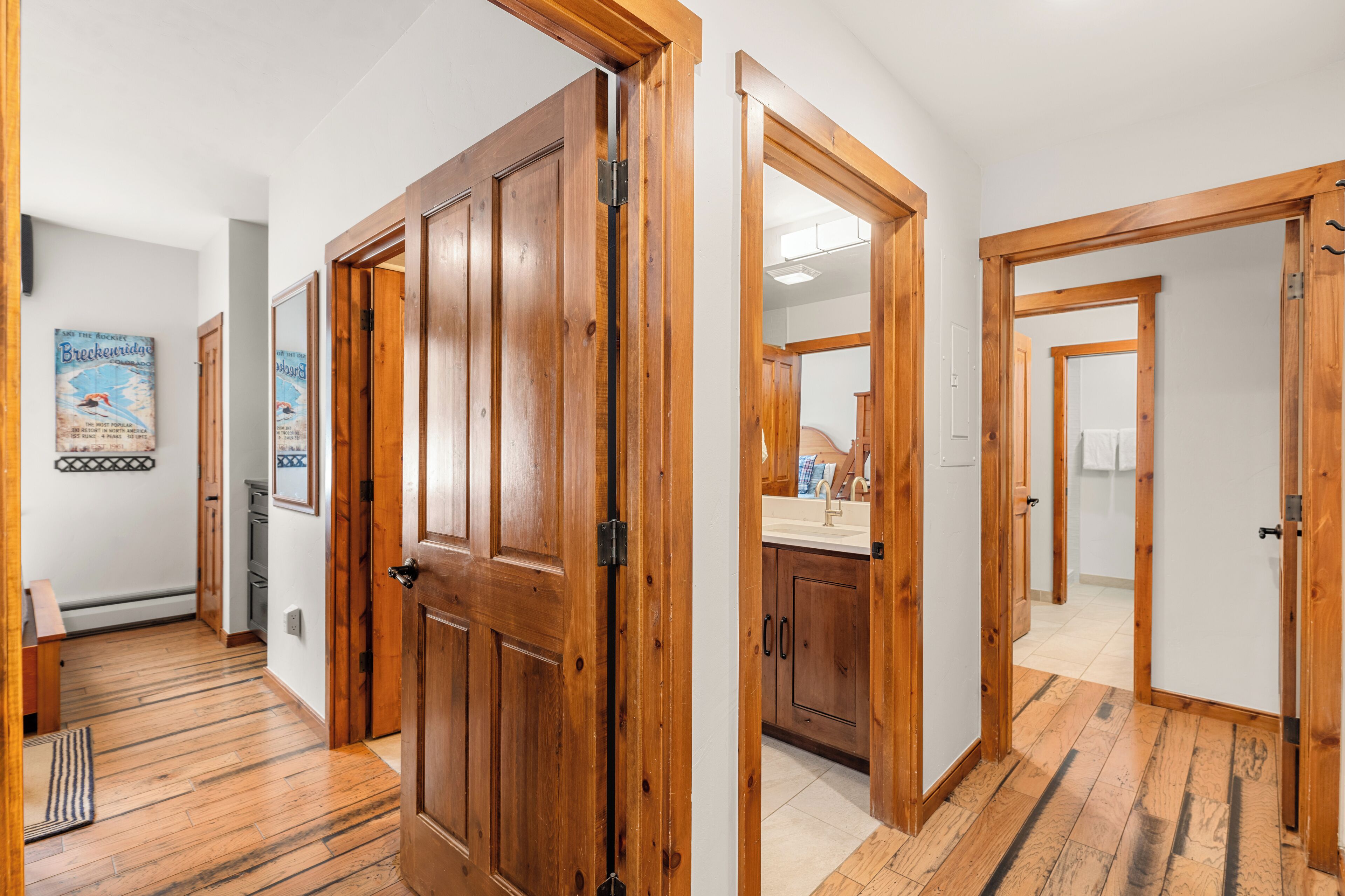 Un couloir avec des portes en bois et un coin cuisine visible à travers l’une des portes.